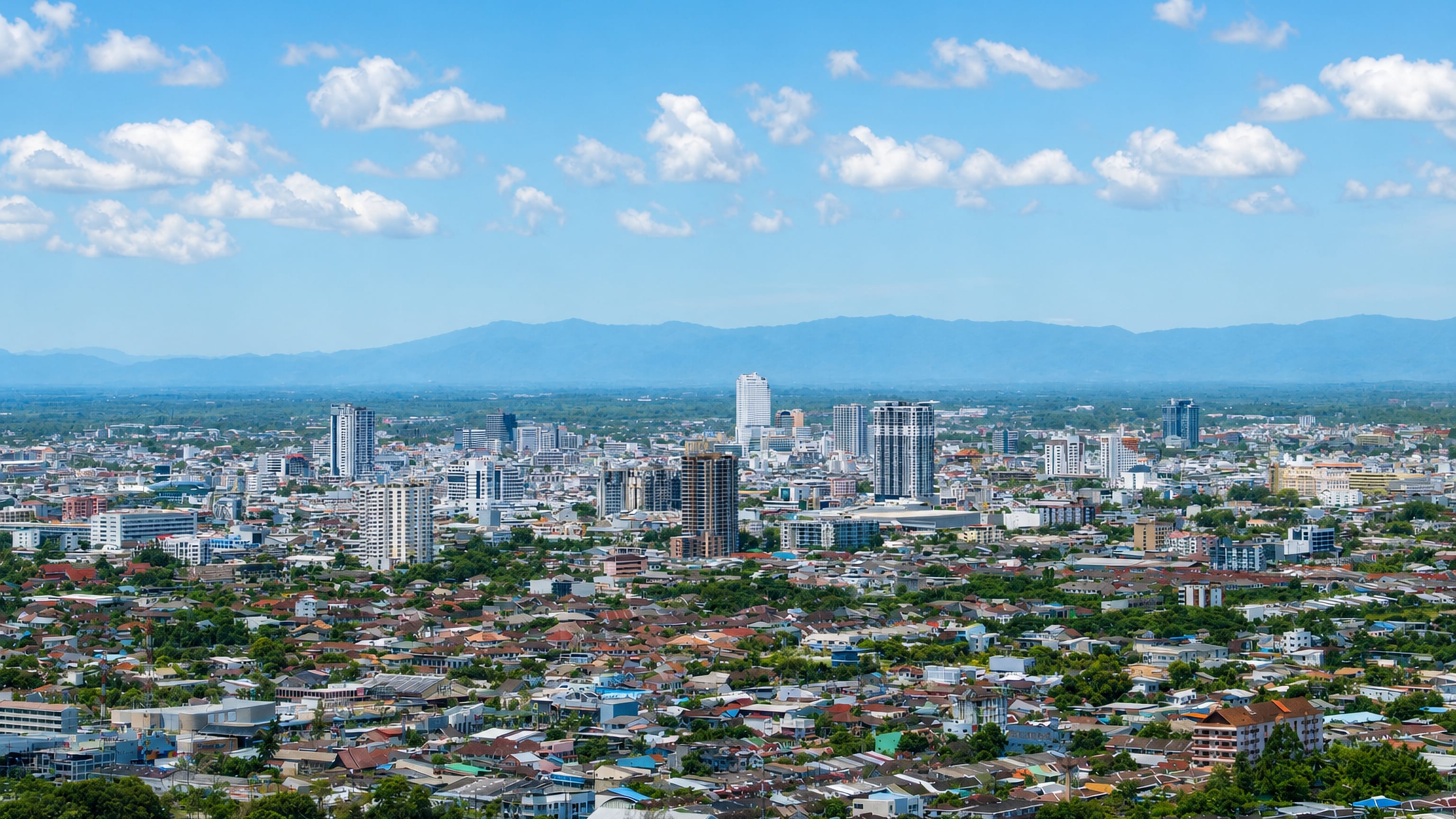 Elevated panorama of Hat Yai, its dense Thai rooftops and central cluster of towers backed by distant mountains