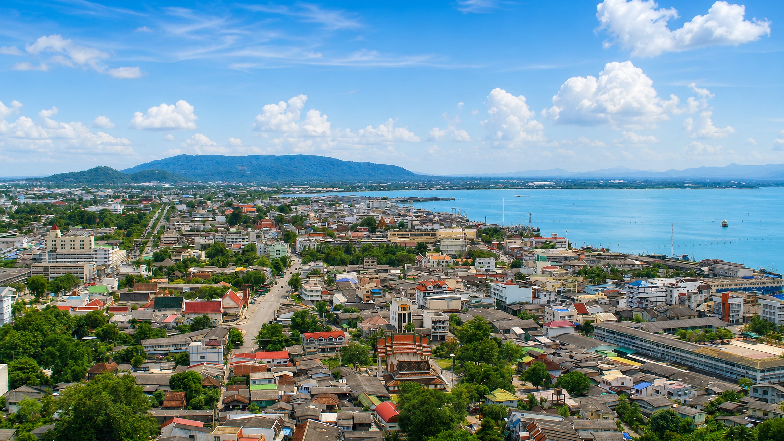 Songkhla, Thailand, from above: old-town rooftops, temple spires and the lakeshore stretching to the hills.