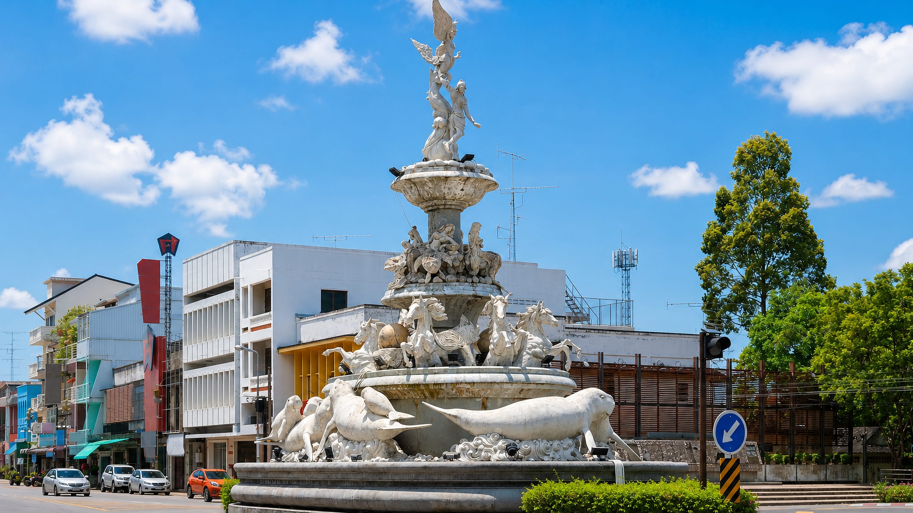 Ornate white dugong fountain on a roundabout with colourful shophouses behind in Trang, southern Thailand.