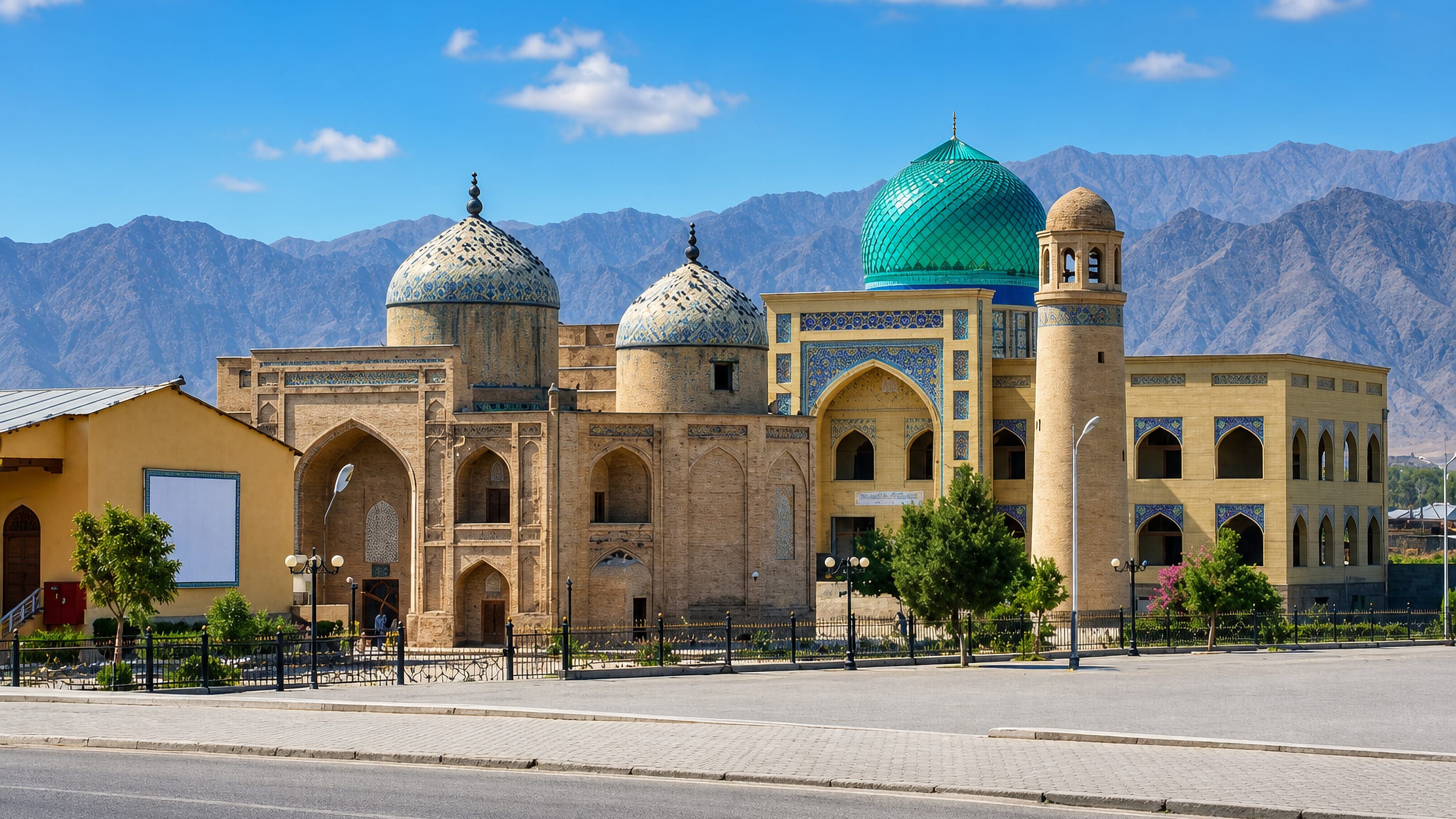 Turquoise-domed mosque and madrasa complex in Khujand, Tajikistan, framed by the arid Turkestan mountain range
