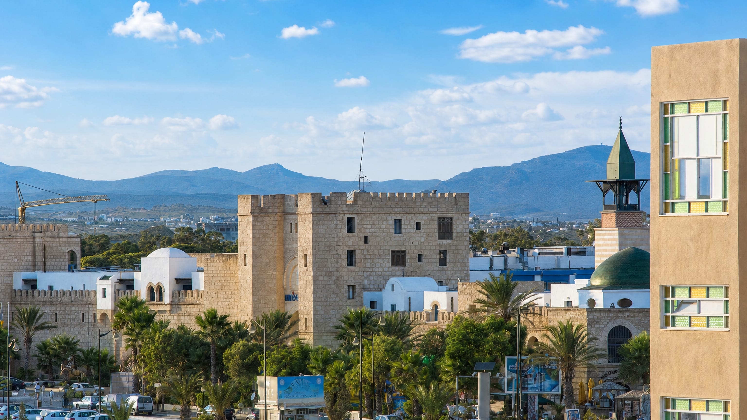 Hammamet's stone kasbah walls, white medina houses and green-domed mosque below inland hills.