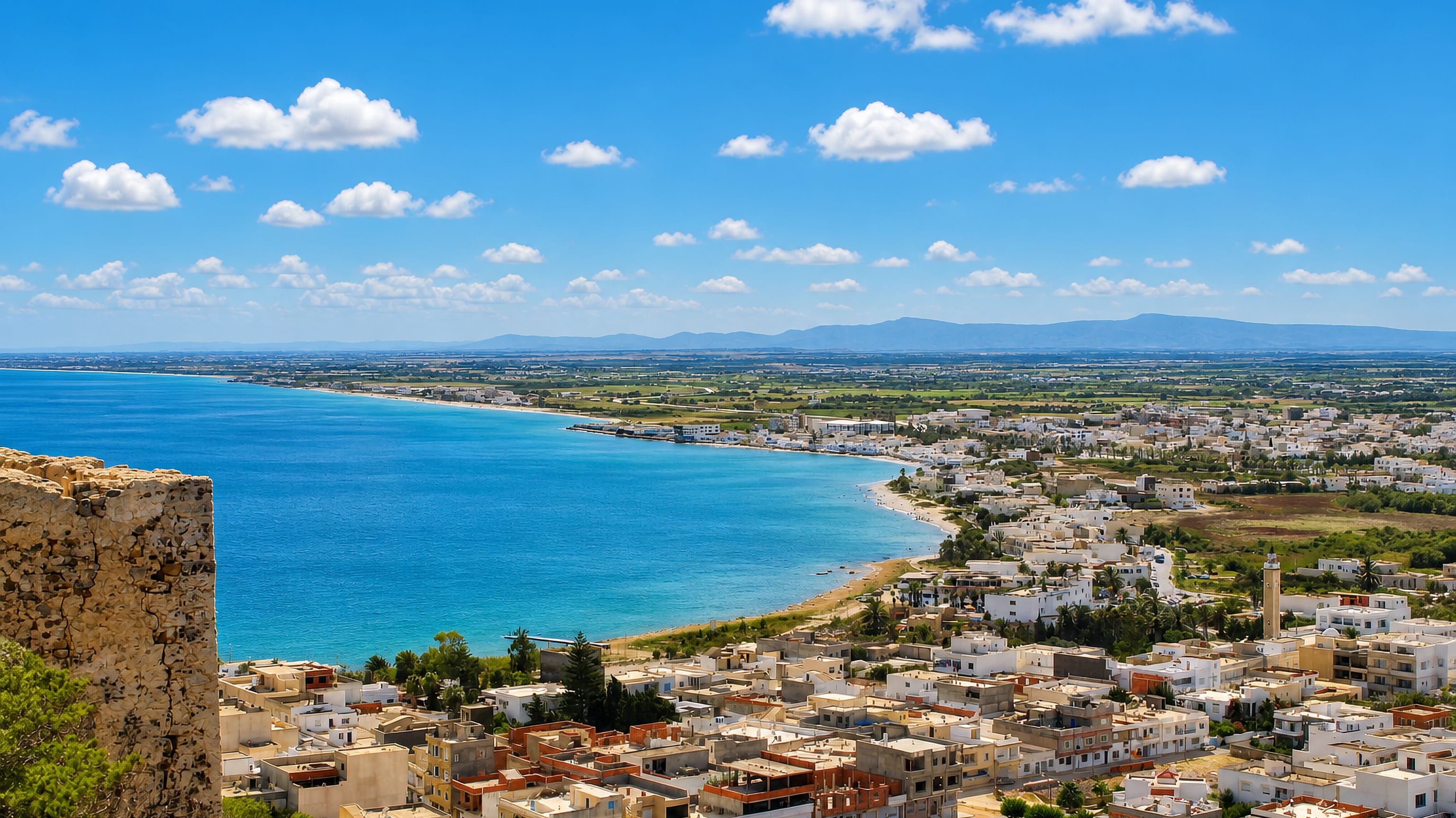 Kélibia, Tunisia, seen from its hilltop fort: white houses, a minaret and a turquoise bay curving to the beach.