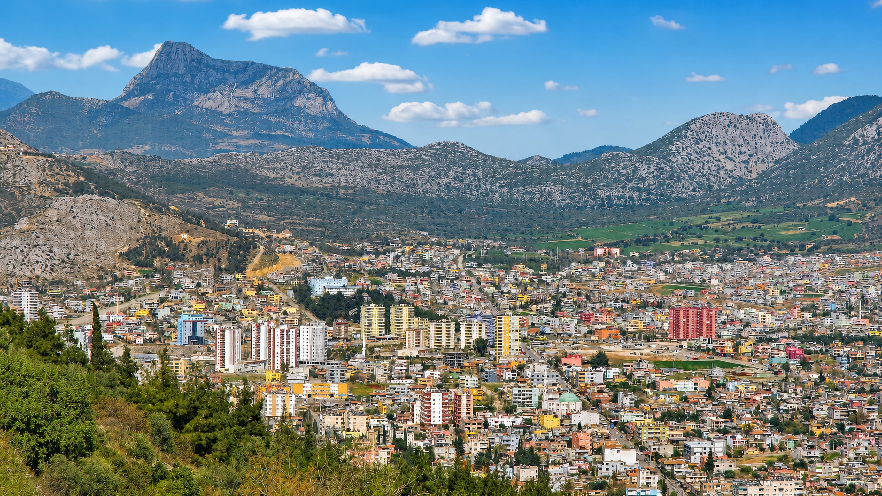 Colourful apartment blocks and houses filling a valley below rocky Taurus peaks in Kozan, Adana, Turkey