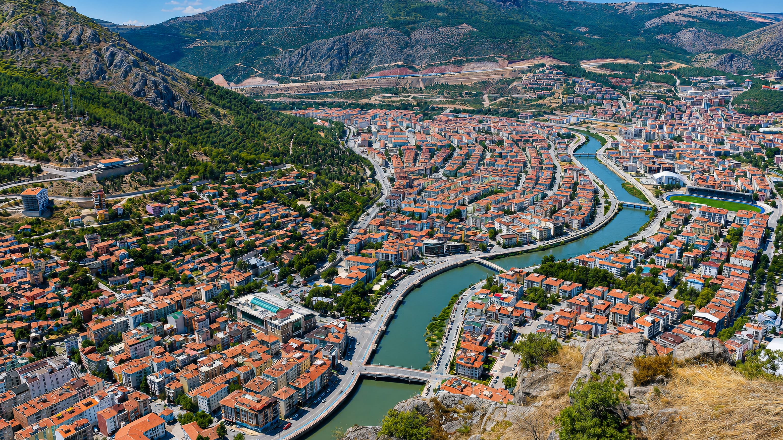 Amasya, Turkey, seen from the cliffs above, its red-roofed houses lining the Yeşilırmak river in a mountain valley.