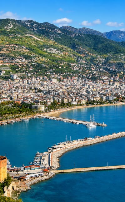 Alanya's harbour, marina and the Red Tower below green mountains on the Turkish coast
