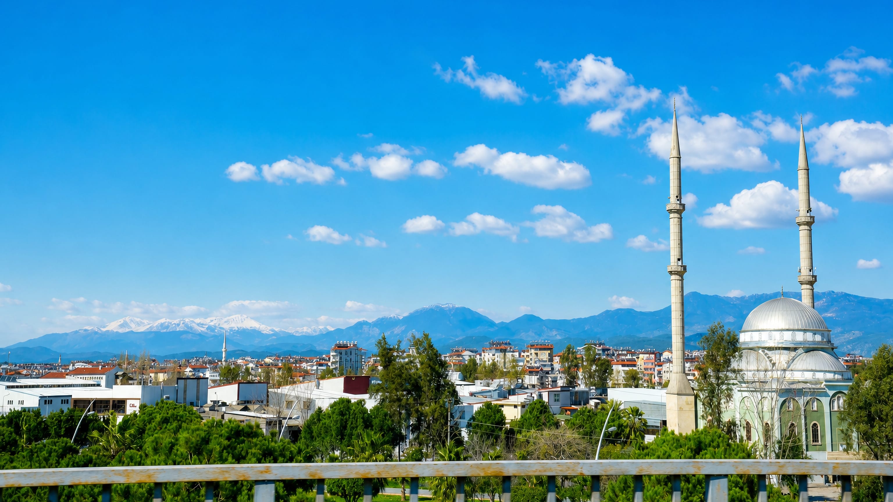Manavgat's twin-minaret mosque and low rooftops with the snow-capped Taurus Mountains behind, Antalya.