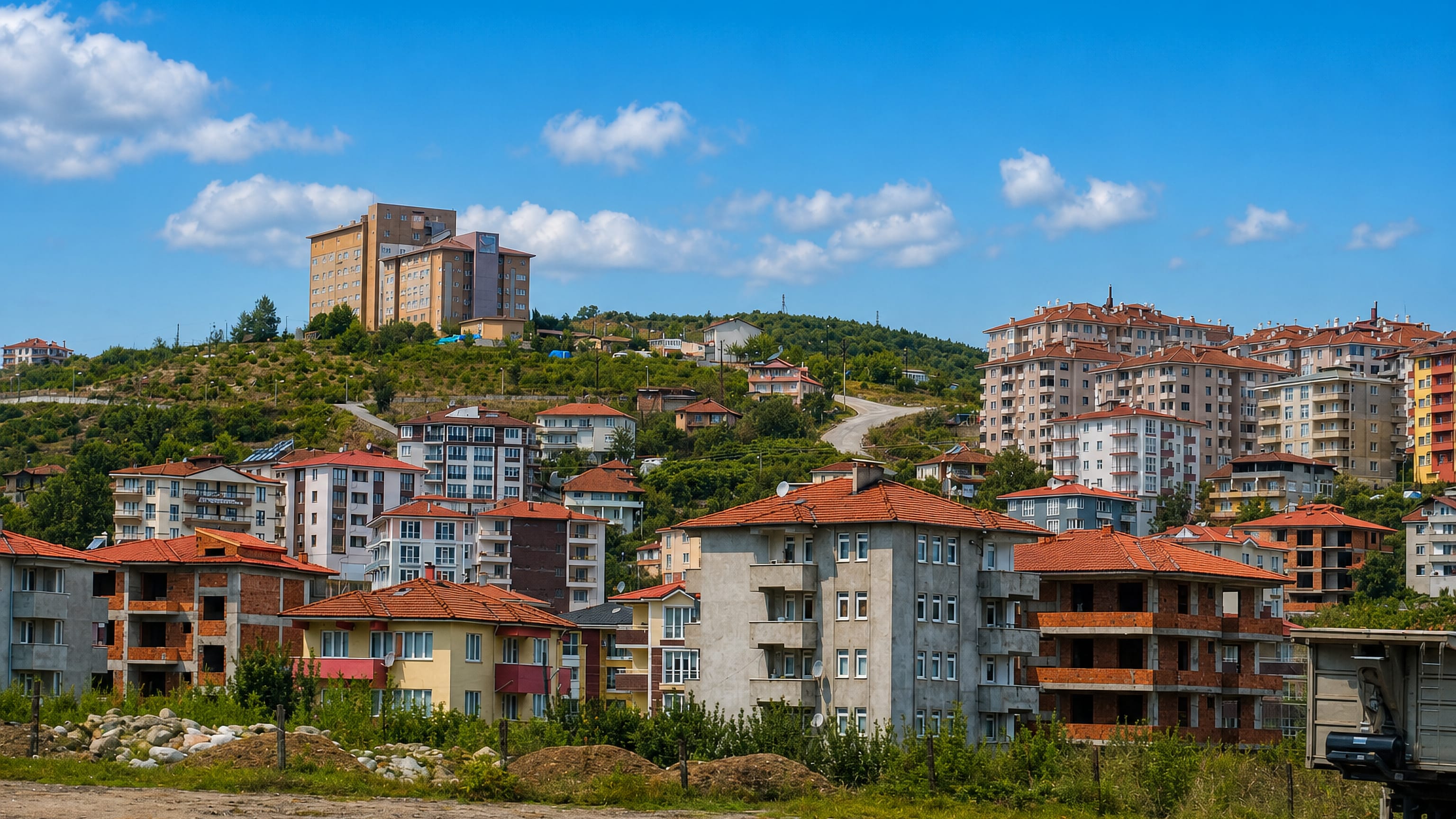 Hillside apartment blocks with red-tiled roofs above a construction lot in Bartın, Turkey.