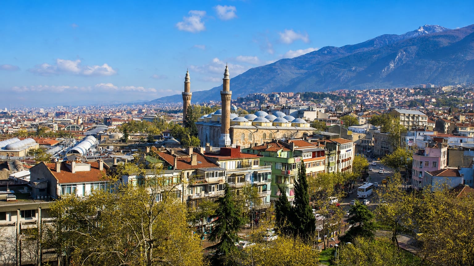 Bursa cityscape with the Grand Mosque's twin minarets below the snow-capped Uludag mountains