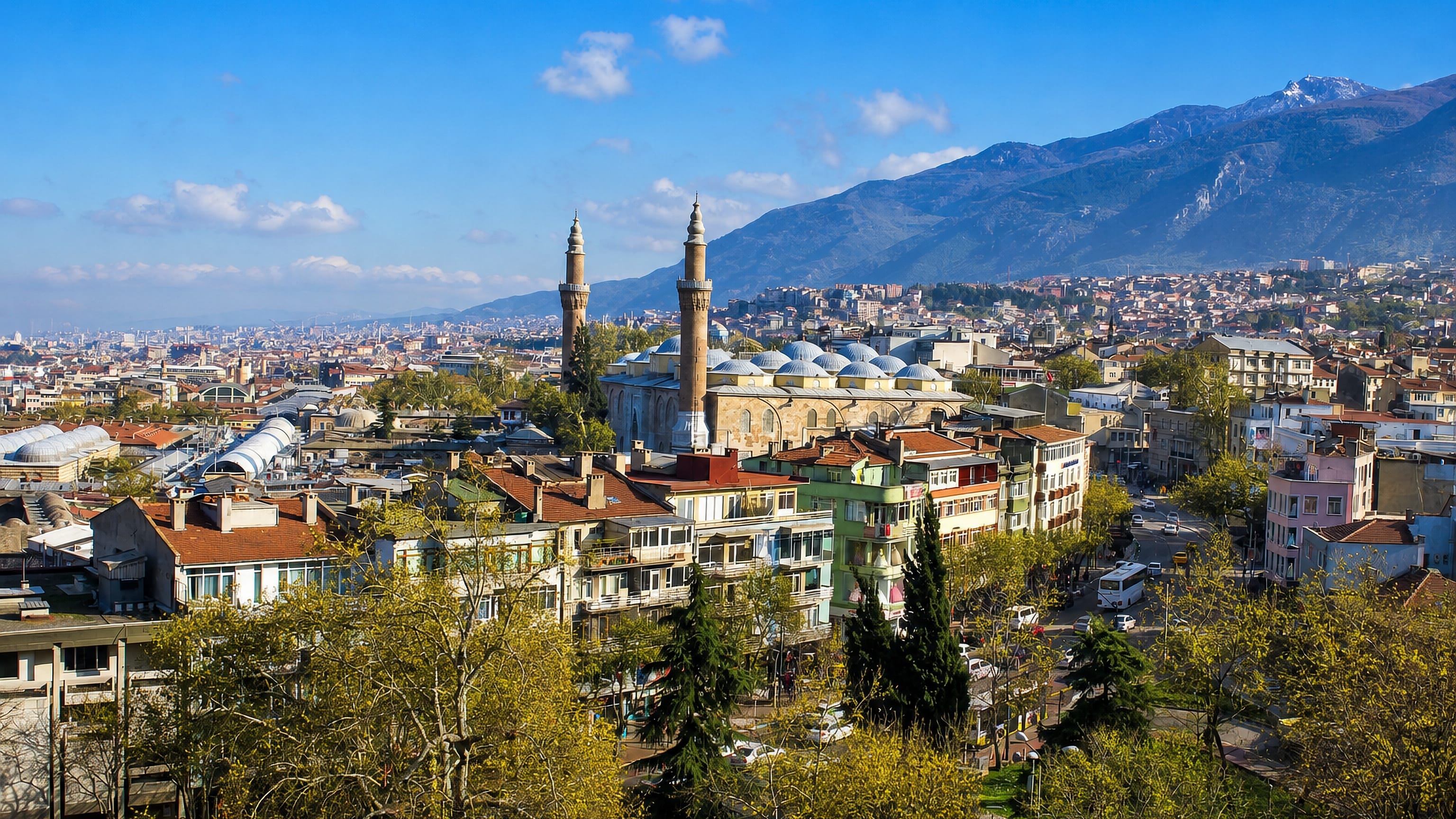 Bursa cityscape with the Grand Mosque's twin minarets below the snow-capped Uludag mountains