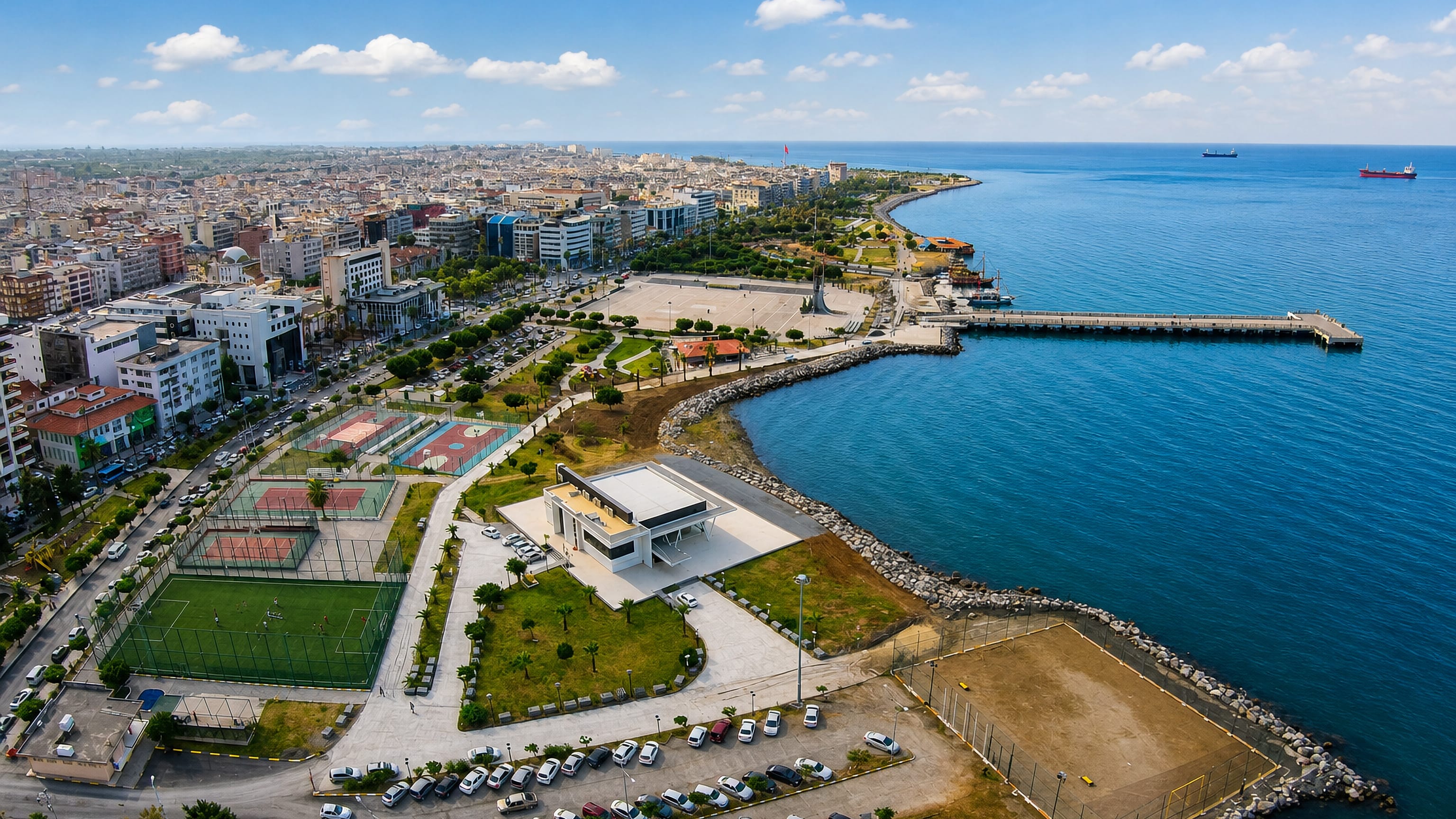 Aerial view of İskenderun, Turkey, with its seafront promenade, park, pier and cargo ships in the gulf.