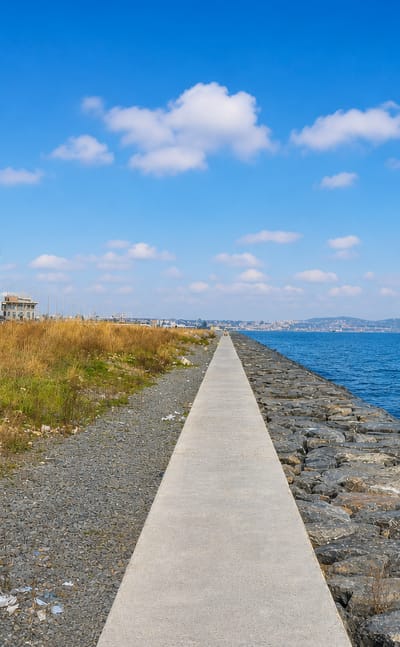 A concrete breakwater path leading to the Marmara Sea with waterfront apartments in Zeytinburnu, Istanbul.