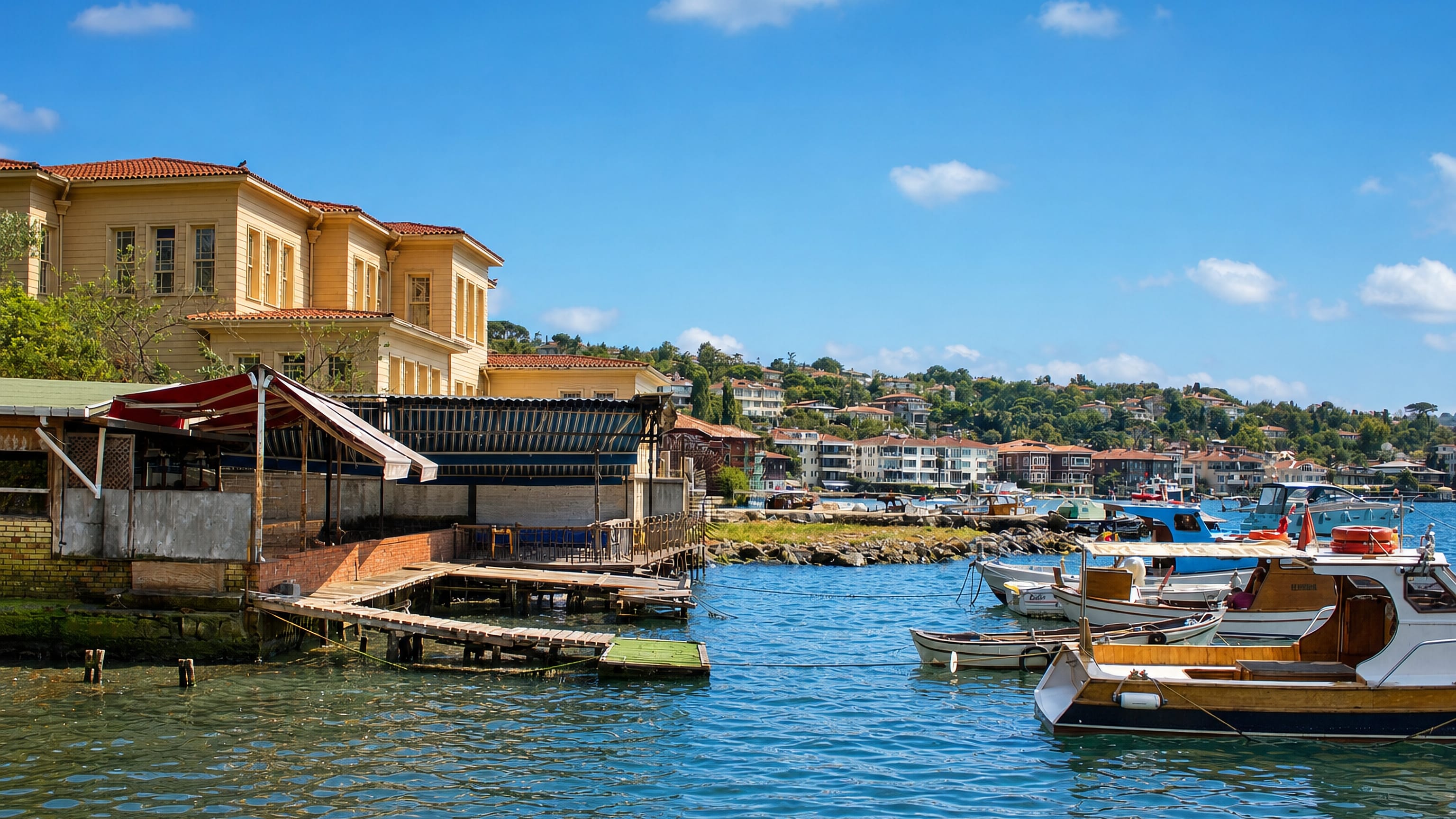 Bosphorus waterfront at Çengelköy, Istanbul, with a wooden yalı mansion, fishing boats and wooded hillside homes