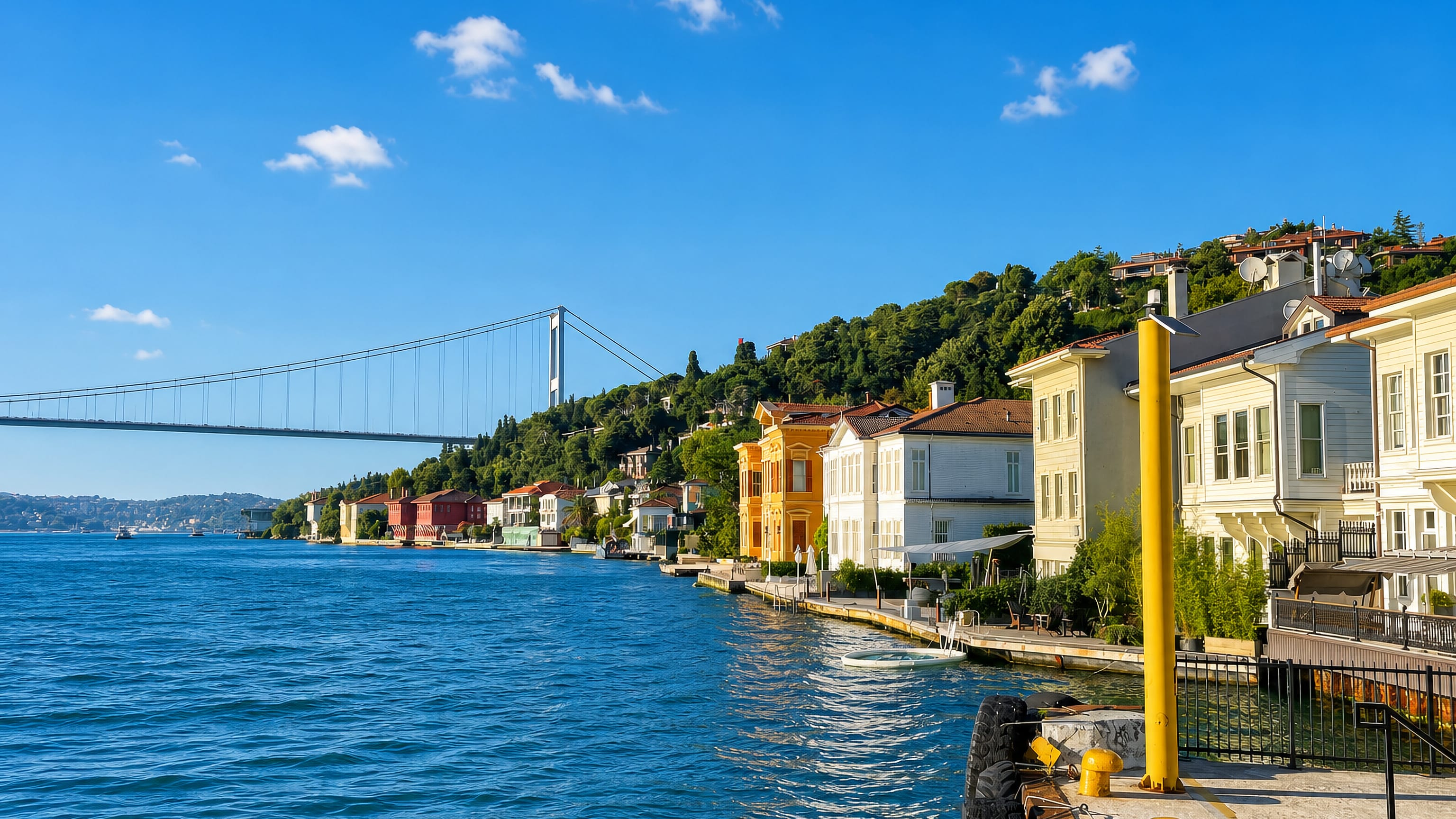 Waterfront yalı mansions lining the Bosphorus shore in Üsküdar, Istanbul, with a suspension bridge beyond.