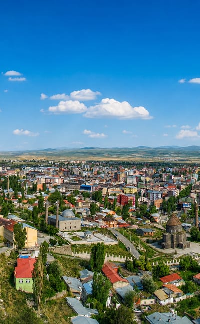 Aerial view of Kars, Turkey, with the hilltop castle walls above the town's houses and domed churches on the open steppe