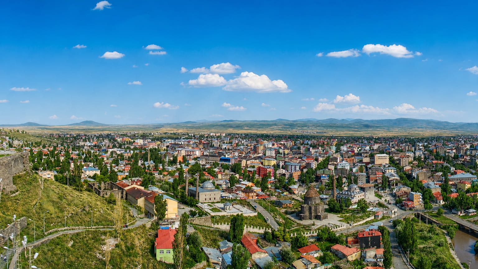 Aerial view of Kars, Turkey, with the hilltop castle walls above the town's houses and domed churches on the open steppe