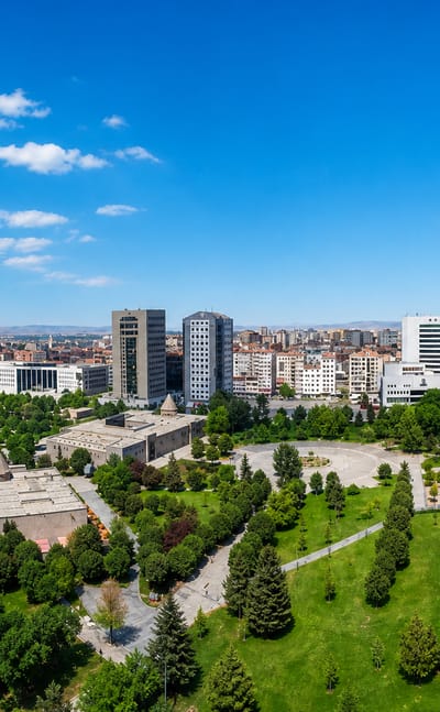 Aerial view of Kayseri with a green city park, pond and mid-rise towers spread toward distant mountains
