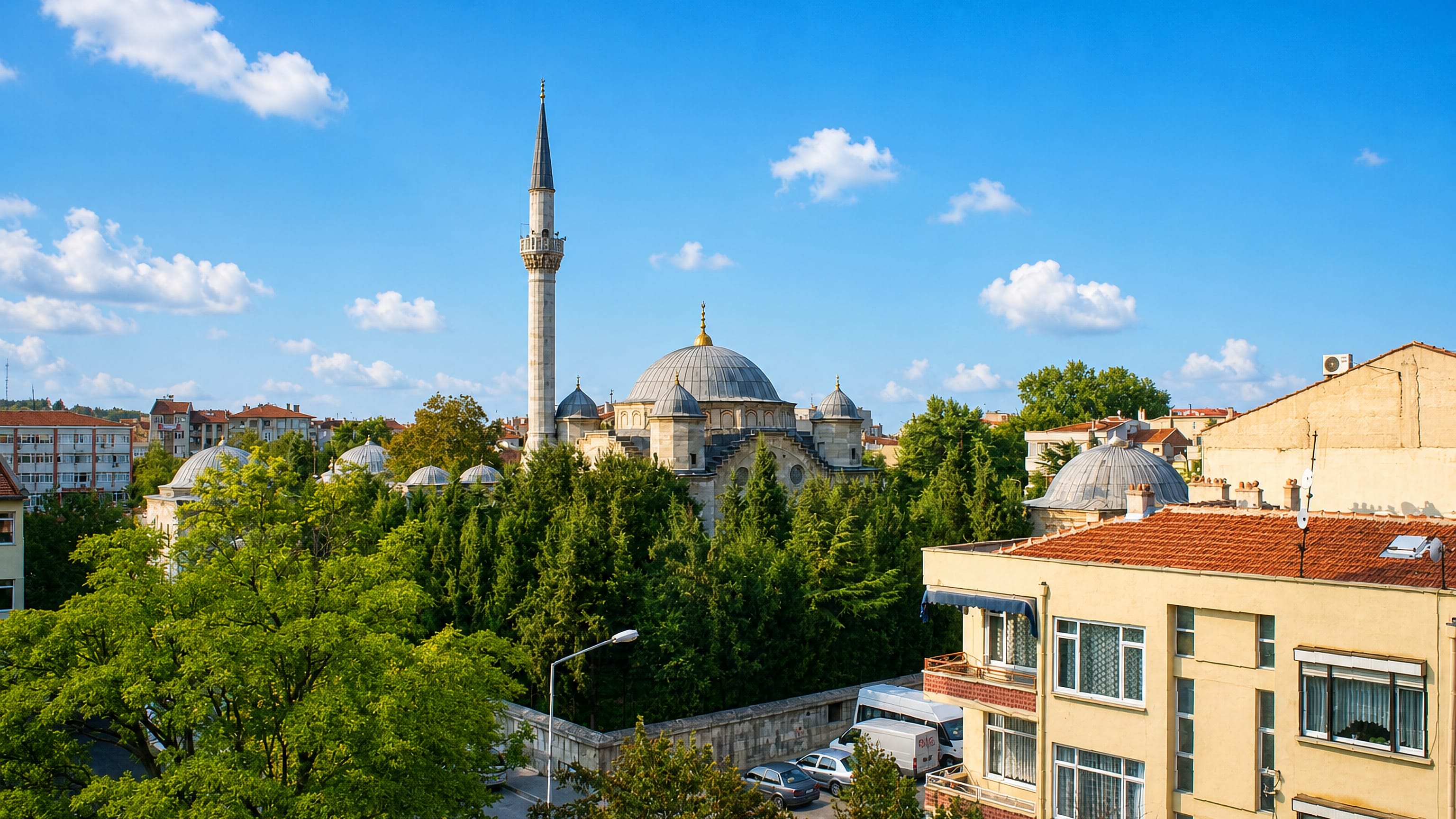 Ottoman domed mosque and single minaret rising above trees and apartment blocks in Lüleburgaz, Turkey.