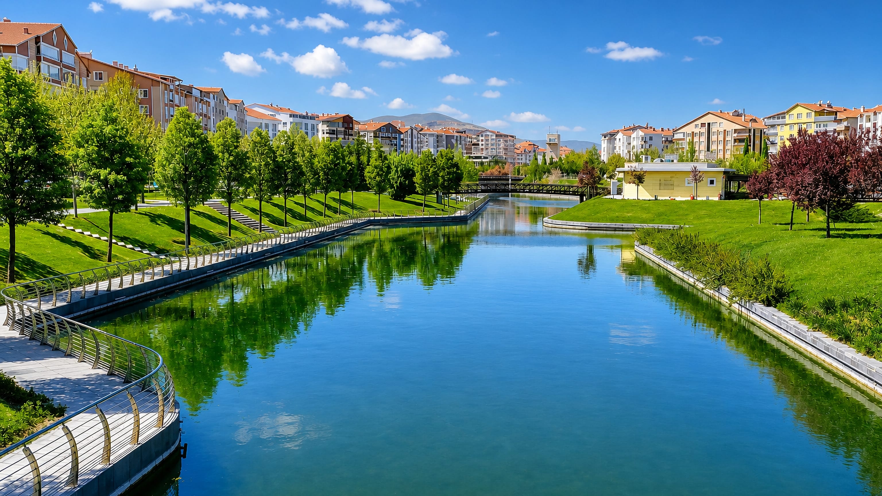Landscaped canal park lined with apartment blocks in Kırşehir, Turkey, with Anatolian hills beyond.