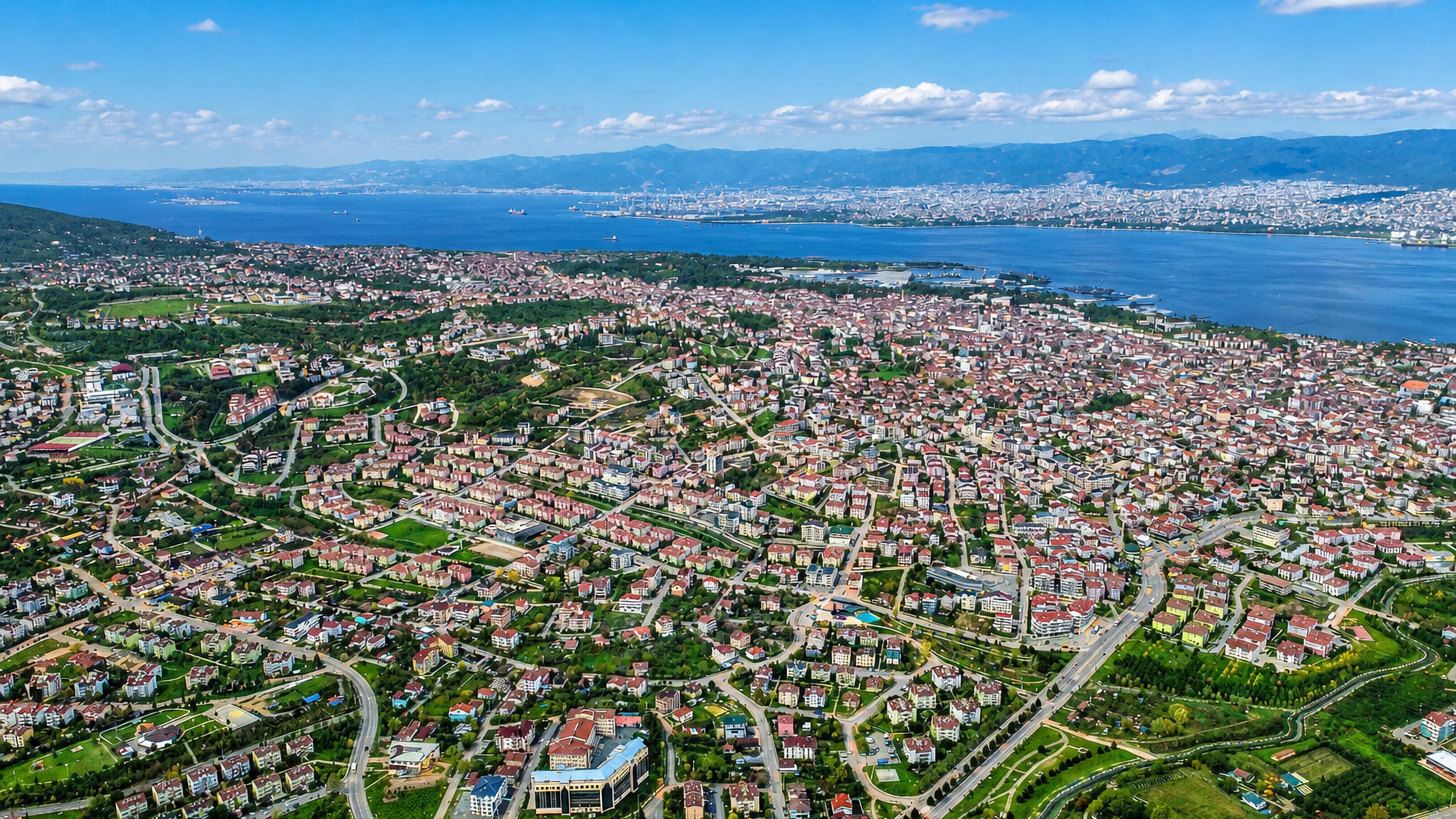 Aerial view of Gölcük, Turkey, red-roofed neighbourhoods along the Gulf of İzmit with mountains across the water.