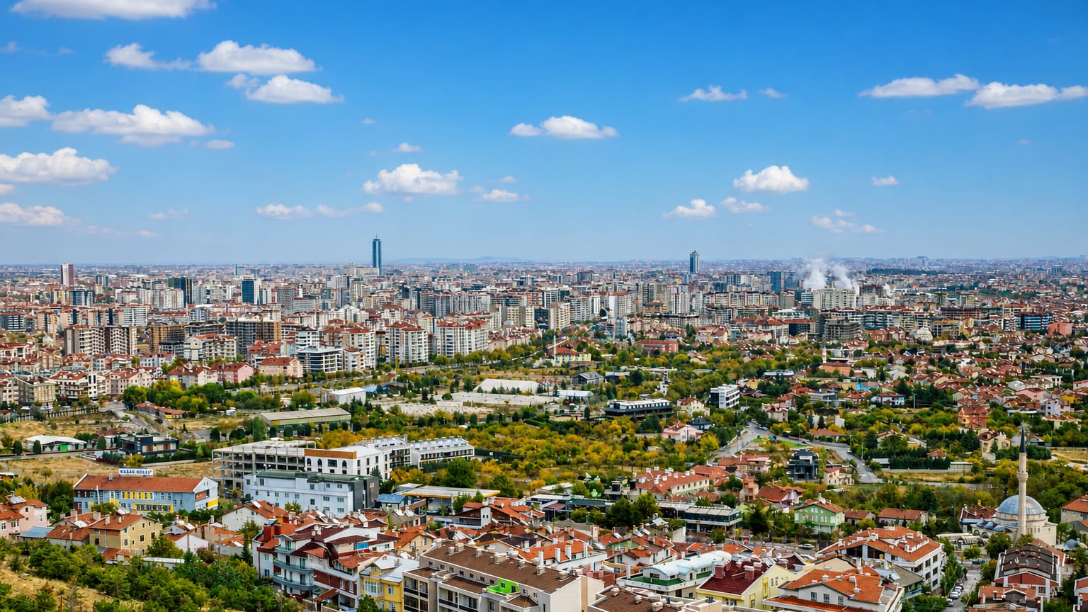 Wide panorama of Konya, Turkey, with sprawling low-rise districts, apartment blocks and a mosque minaret.