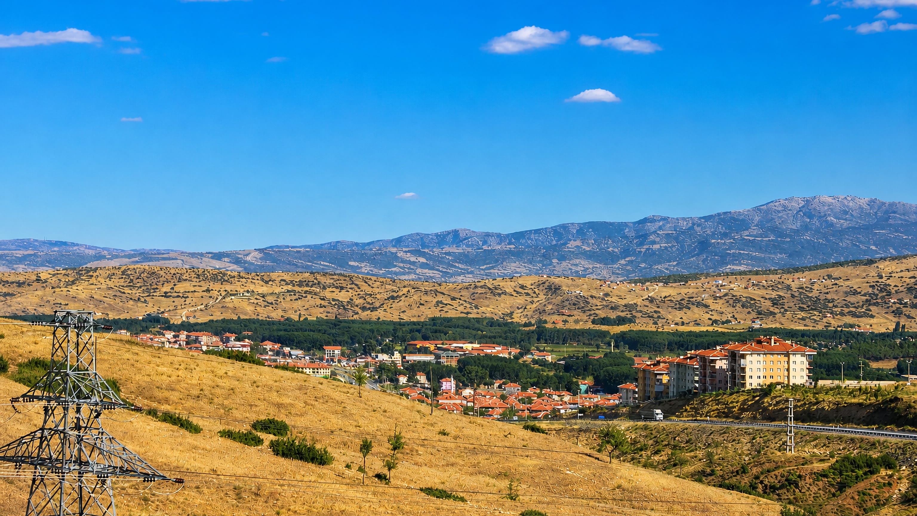 Red-roofed houses and apartment blocks of Salihli, Manisa, below parched hills and distant mountains.