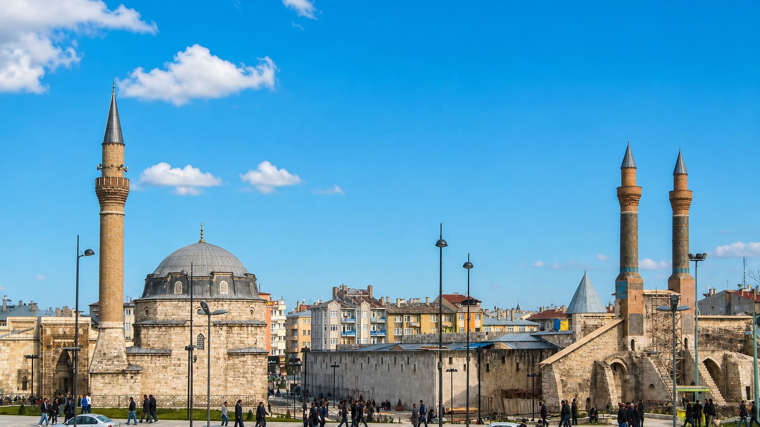 Sivas main square with a domed mosque and the twin fluted brick minarets of the Çifte Minareli Medrese under a blue sky