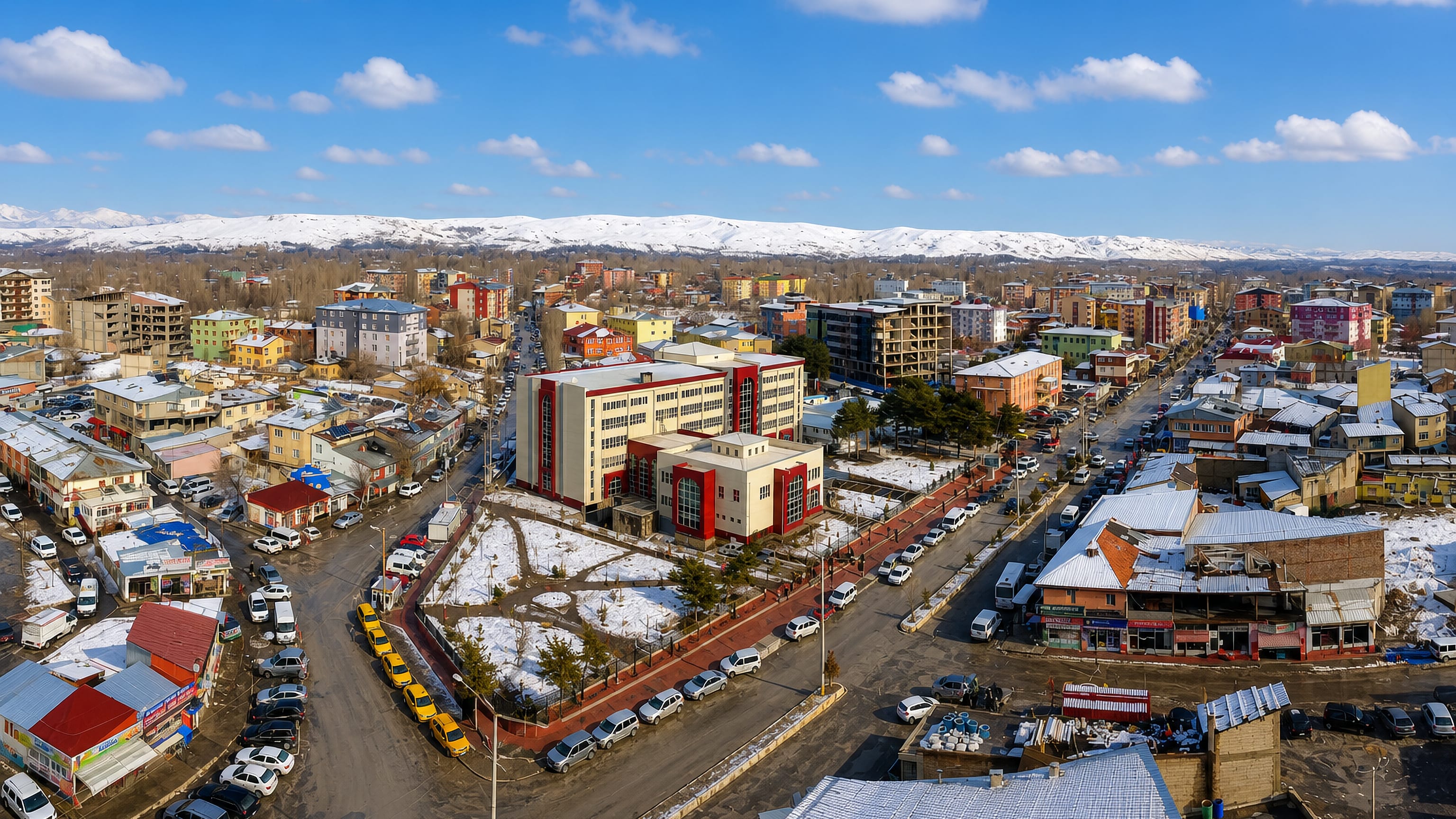 Aerial view of snow-covered Erciş, Turkey, its low-rise streets backed by white eastern Anatolian ranges.