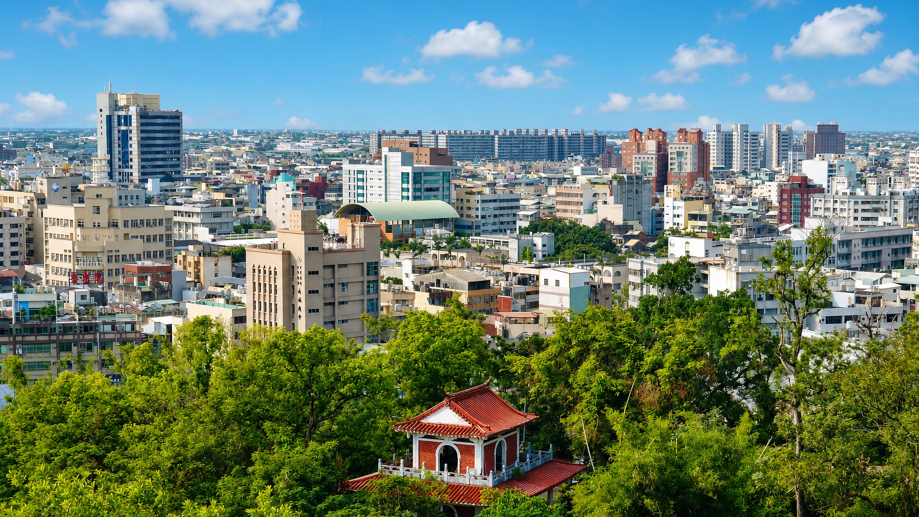 Changhua's dense rooftops seen from a wooded hillside with a red-roofed Chinese pavilion in the foreground