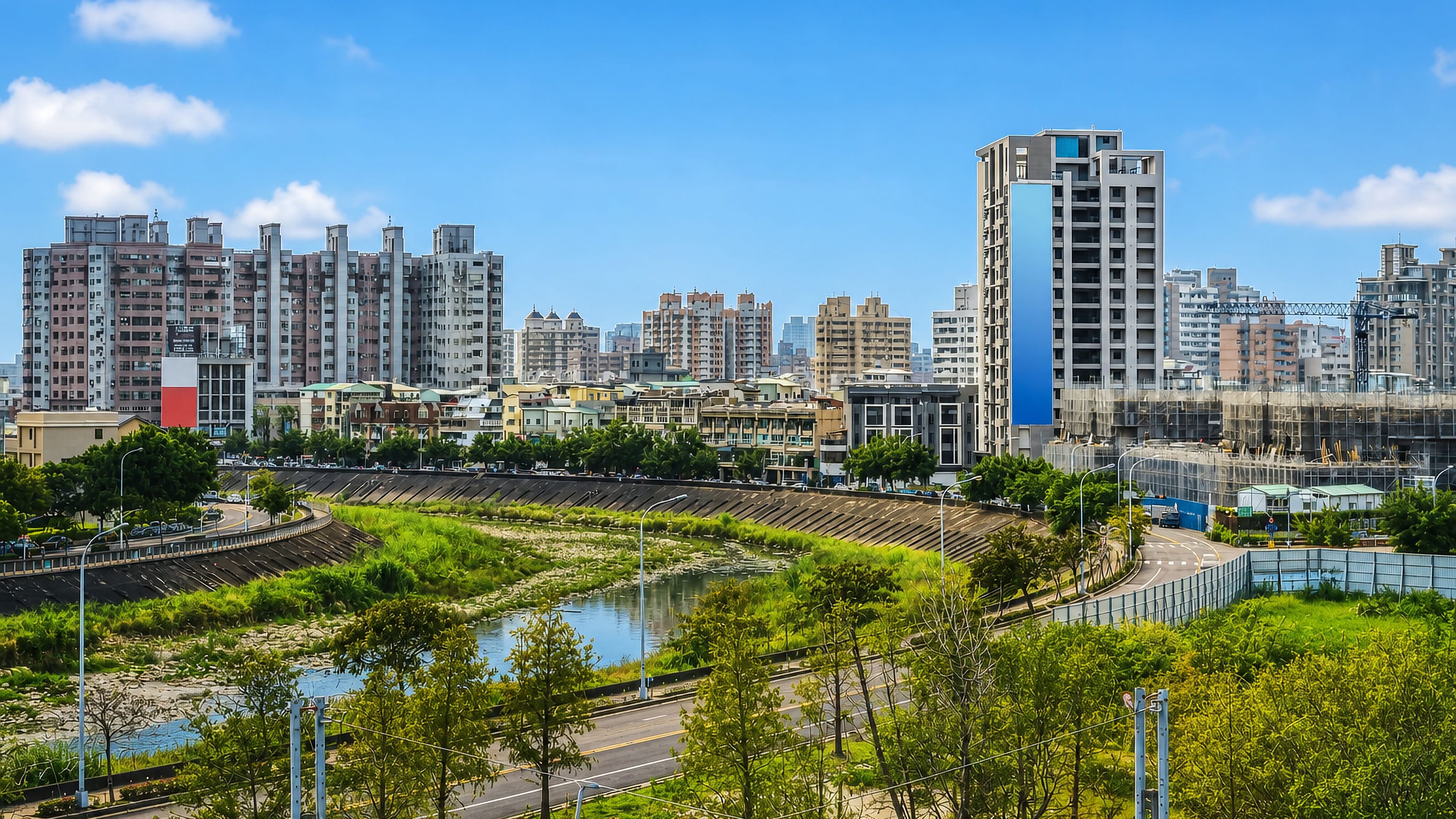 Apartment towers along a channelised river in Beitun District, Taichung, Taiwan, under a bright blue sky.