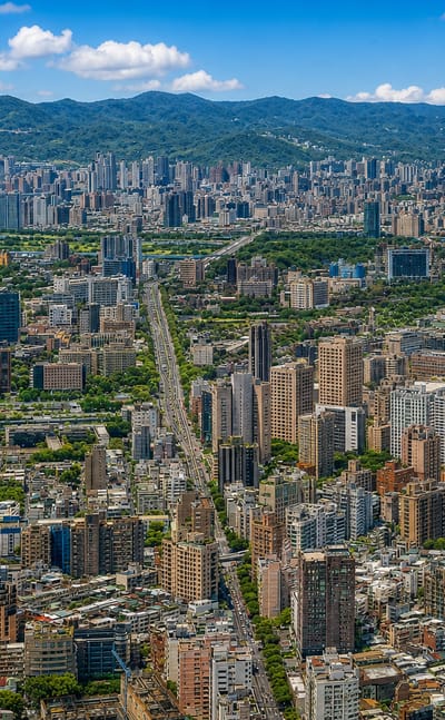 Aerial daytime view of Taipei's dense low-rise Da'an District in a green mountain-ringed basin