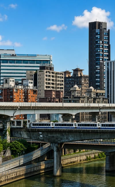Modern towers, elevated rail and a train beside the river in Taipei's Nangang District