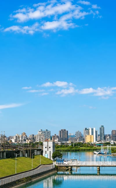 Riverside parkland and distant skyline with bridges over the river in Taipei's Shilin District