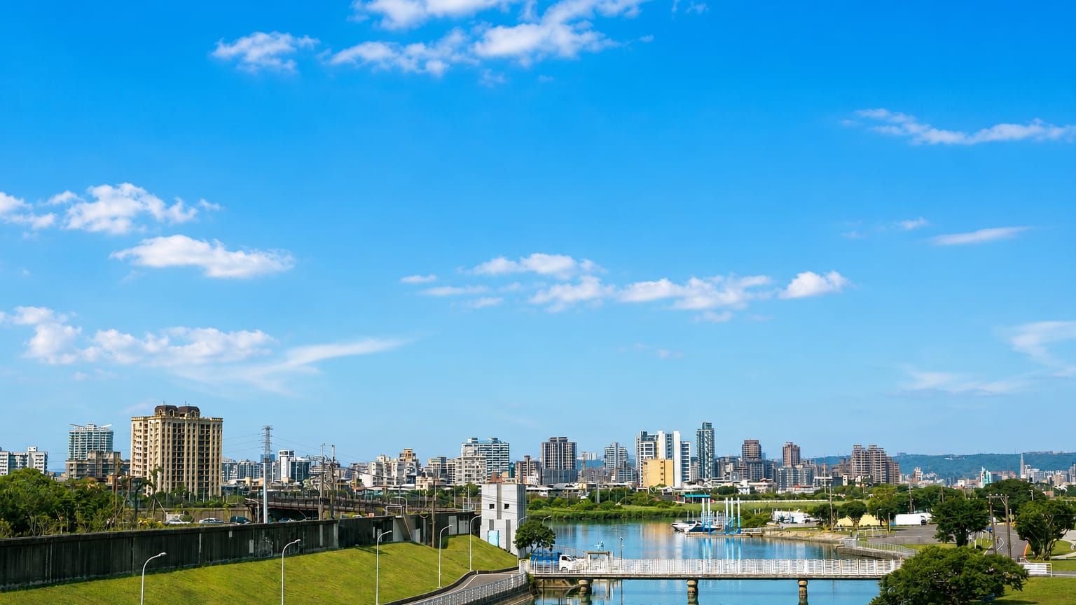 Riverside parkland and distant skyline with bridges over the river in Taipei's Shilin District