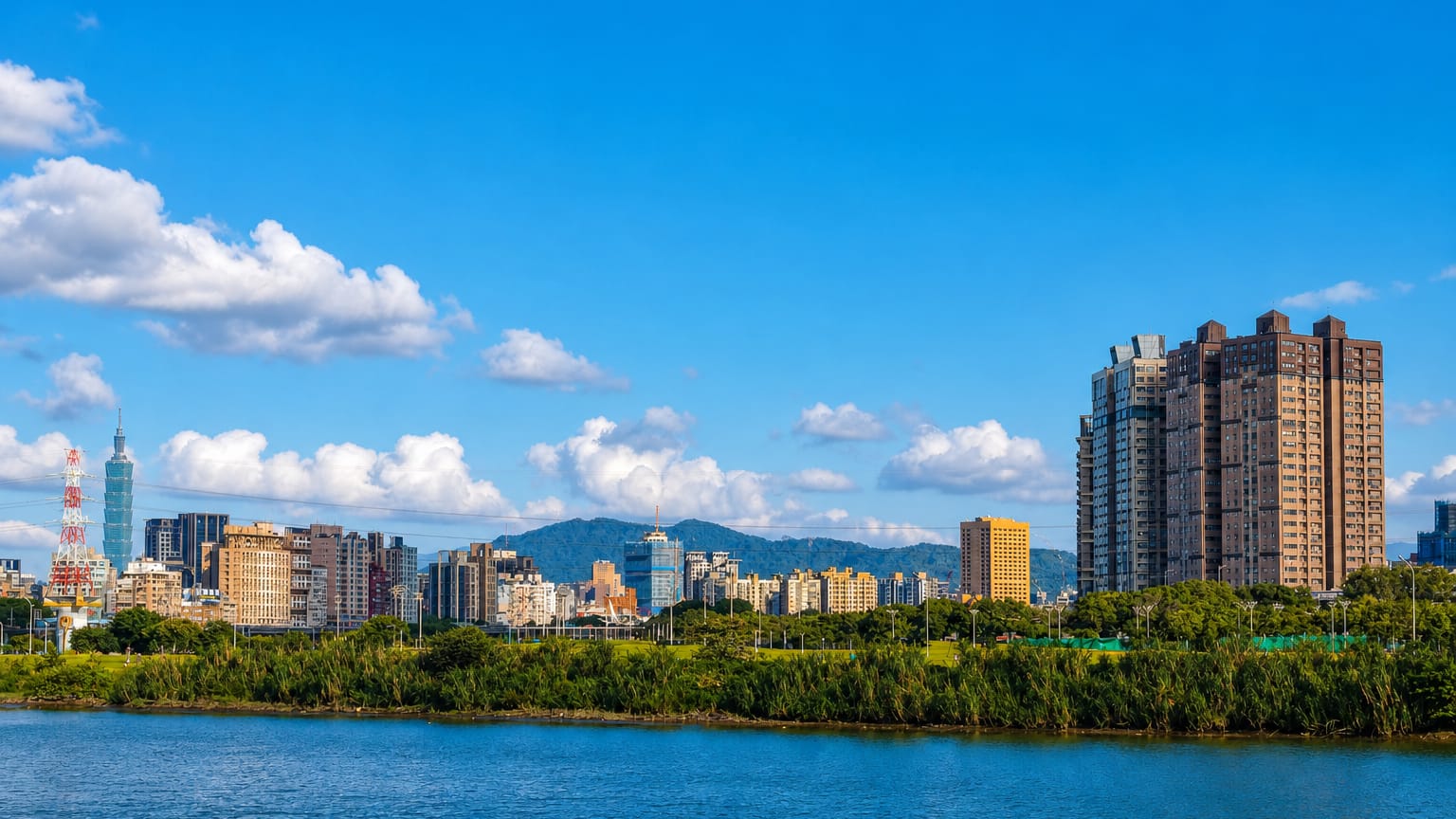 Riverside skyline of Taipei's Wanhua District with Taipei 101 rising beyond a tree-lined riverbank