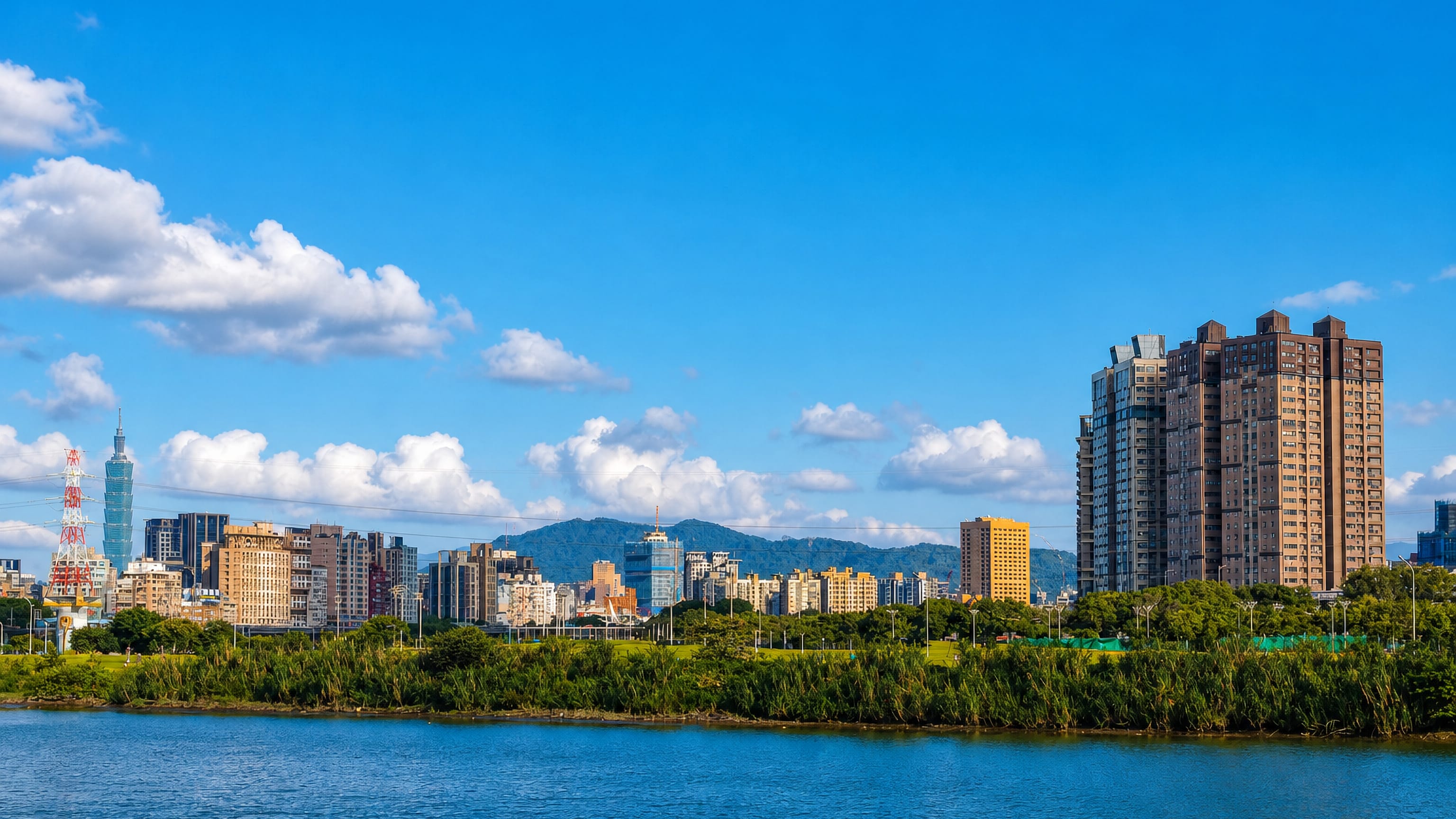 Riverside skyline of Taipei's Wanhua District with Taipei 101 rising beyond a tree-lined riverbank
