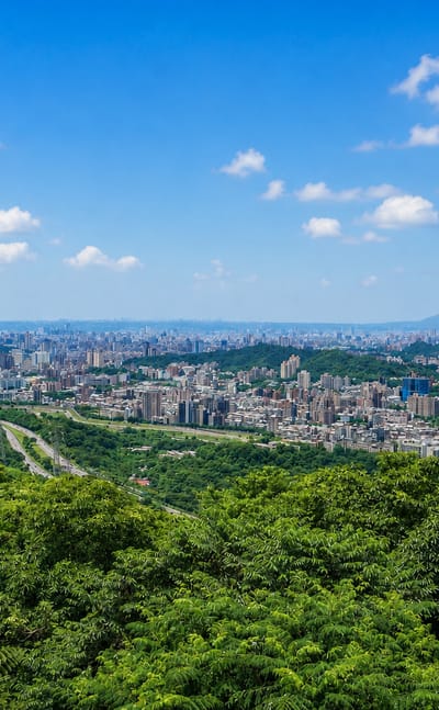 Forested green hills of Taipei's Wenshan District overlooking the distant city in the basin