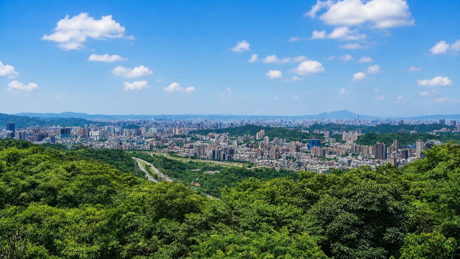 Forested green hills of Taipei's Wenshan District overlooking the distant city in the basin