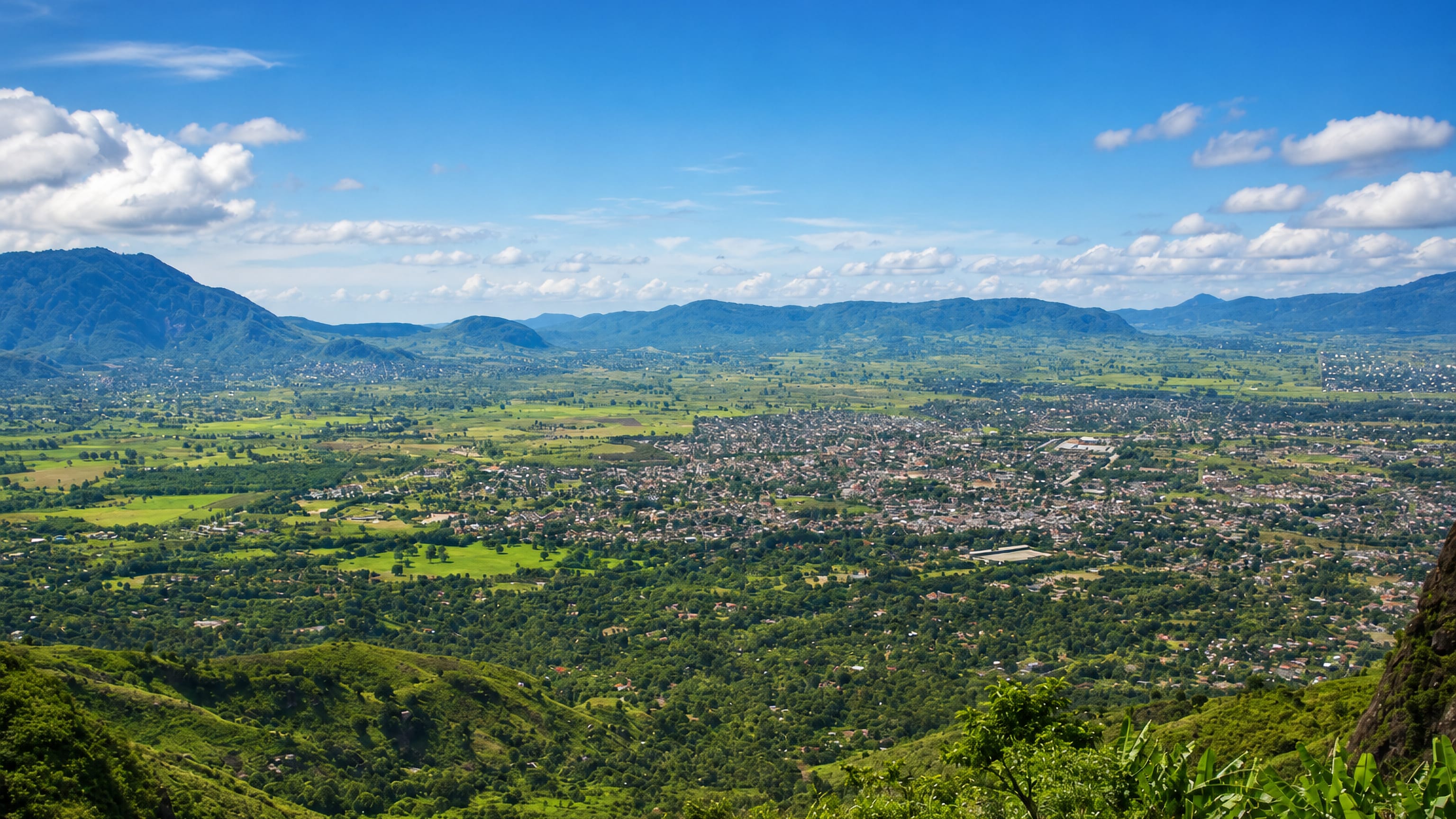 Morogoro spread across a green valley of fields and trees below distant blue mountain ridges in Tanzania.