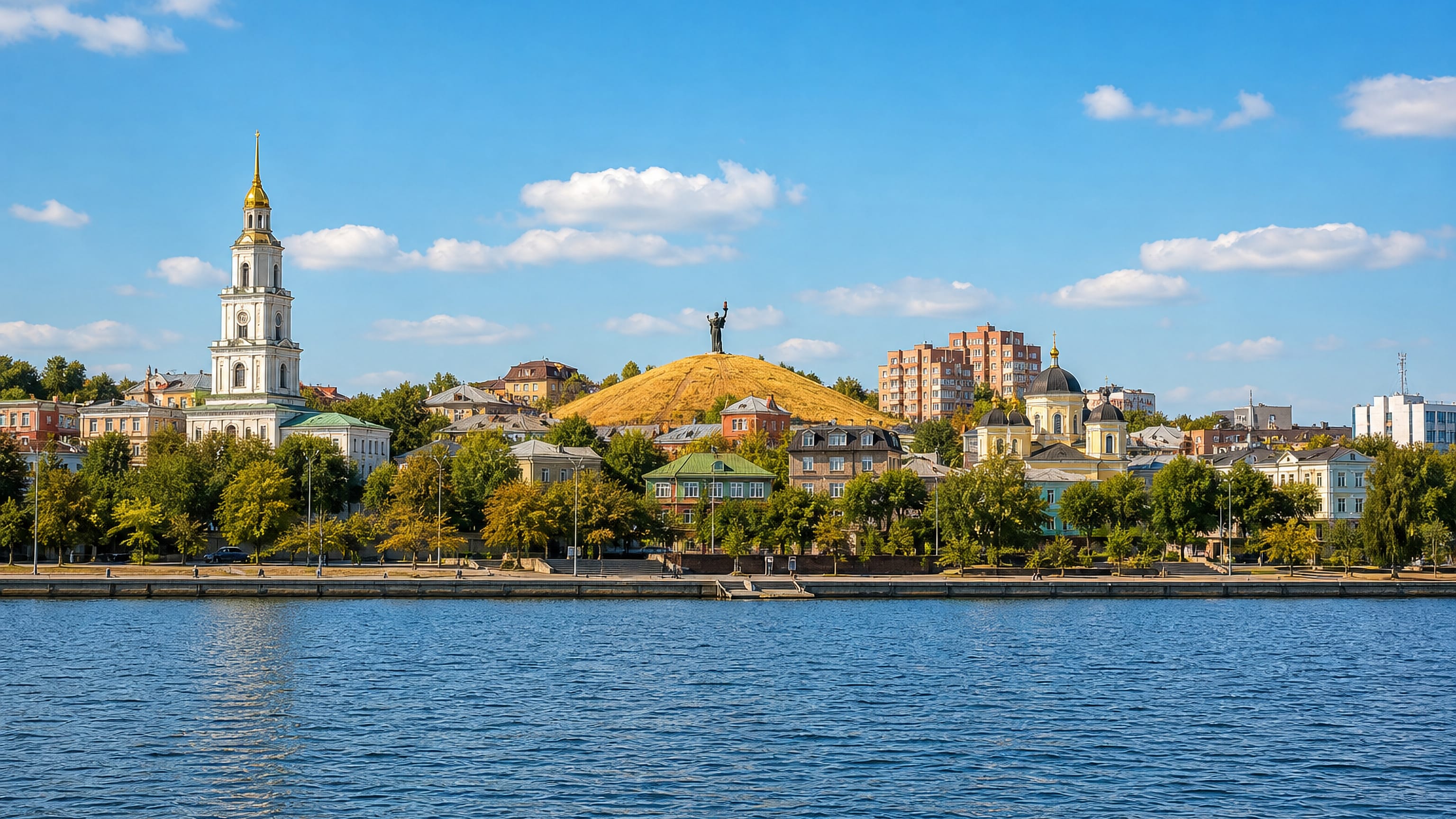 Cherkasy's Dnieper waterfront, with a bell tower, hilltop monument and tree-lined riverside embankment