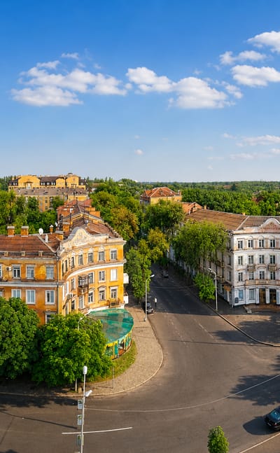 Aerial of a tree-lined square with historic buildings and a factory chimney in Kryvyy Rih, Ukraine