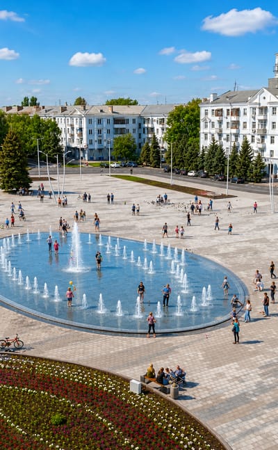 Central square in Kramatorsk, Ukraine, with a large fountain, flower beds and apartment blocks