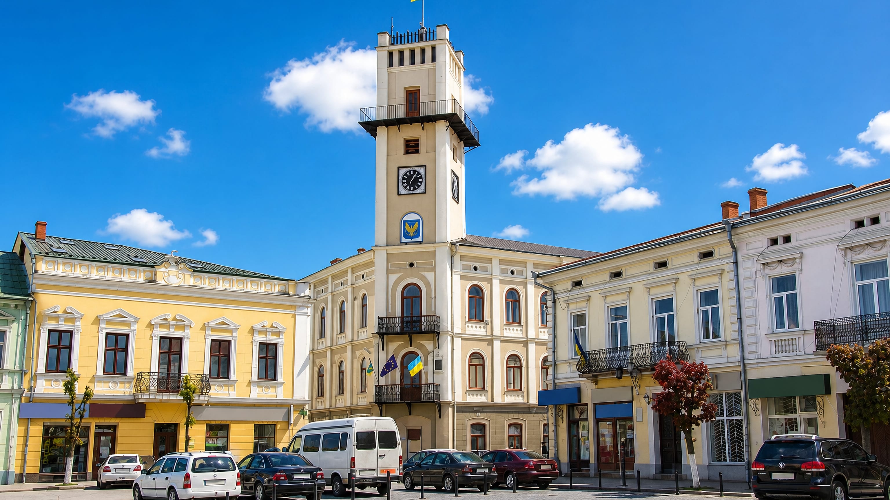 Kolomyia's town hall clock tower and pastel townhouses lining the cobbled central market square.