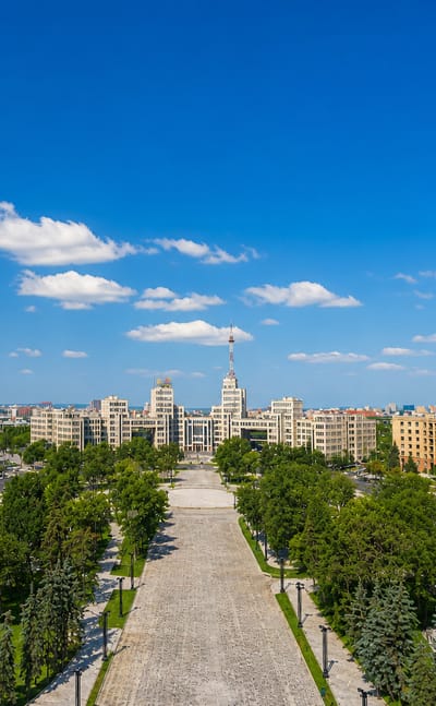 Kharkiv's Freedom Square framed by monumental Constructivist buildings and a central spired tower on a sunny day.
