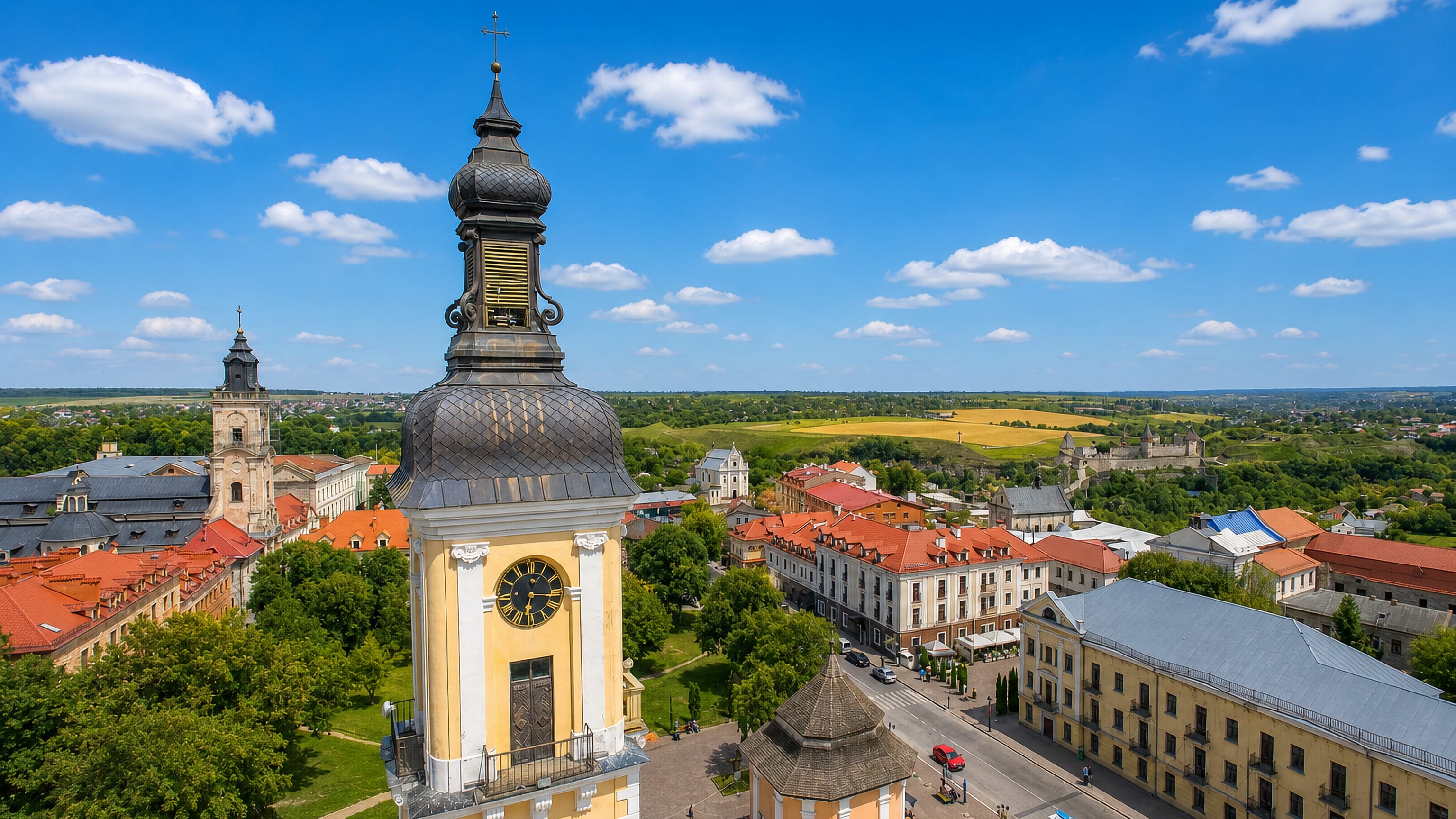 Aerial view of Kamianets-Podilskyi, Ukraine, with the old town's yellow bell tower and the fortress beyond red roofs