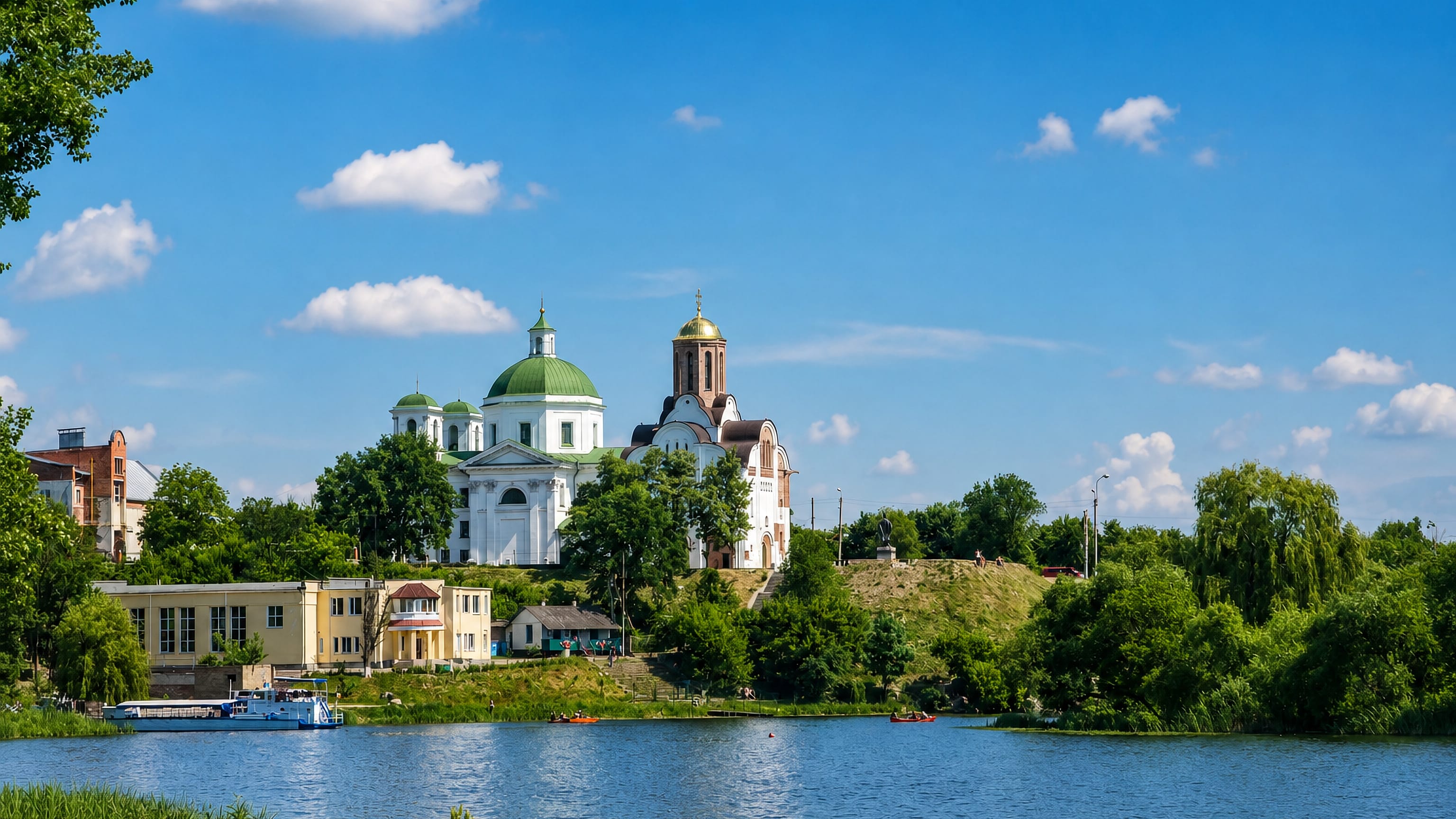 White classical cathedral and gold-domed church above the green banks of the Ros River in Bila Tserkva.