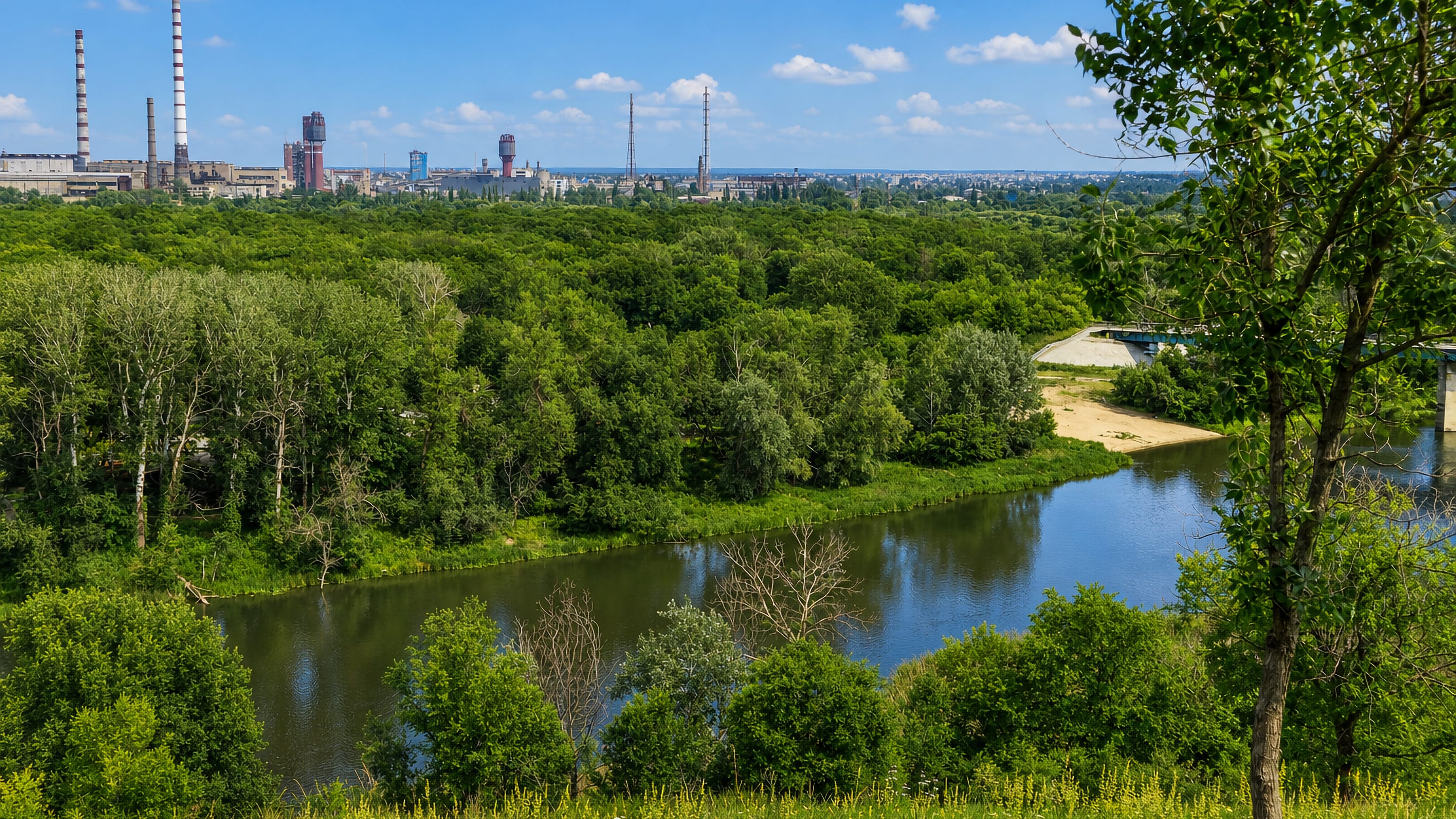 Wooded Siverskyi Donets valley below Lysychansk, Ukraine, with industrial chimneys on the skyline.