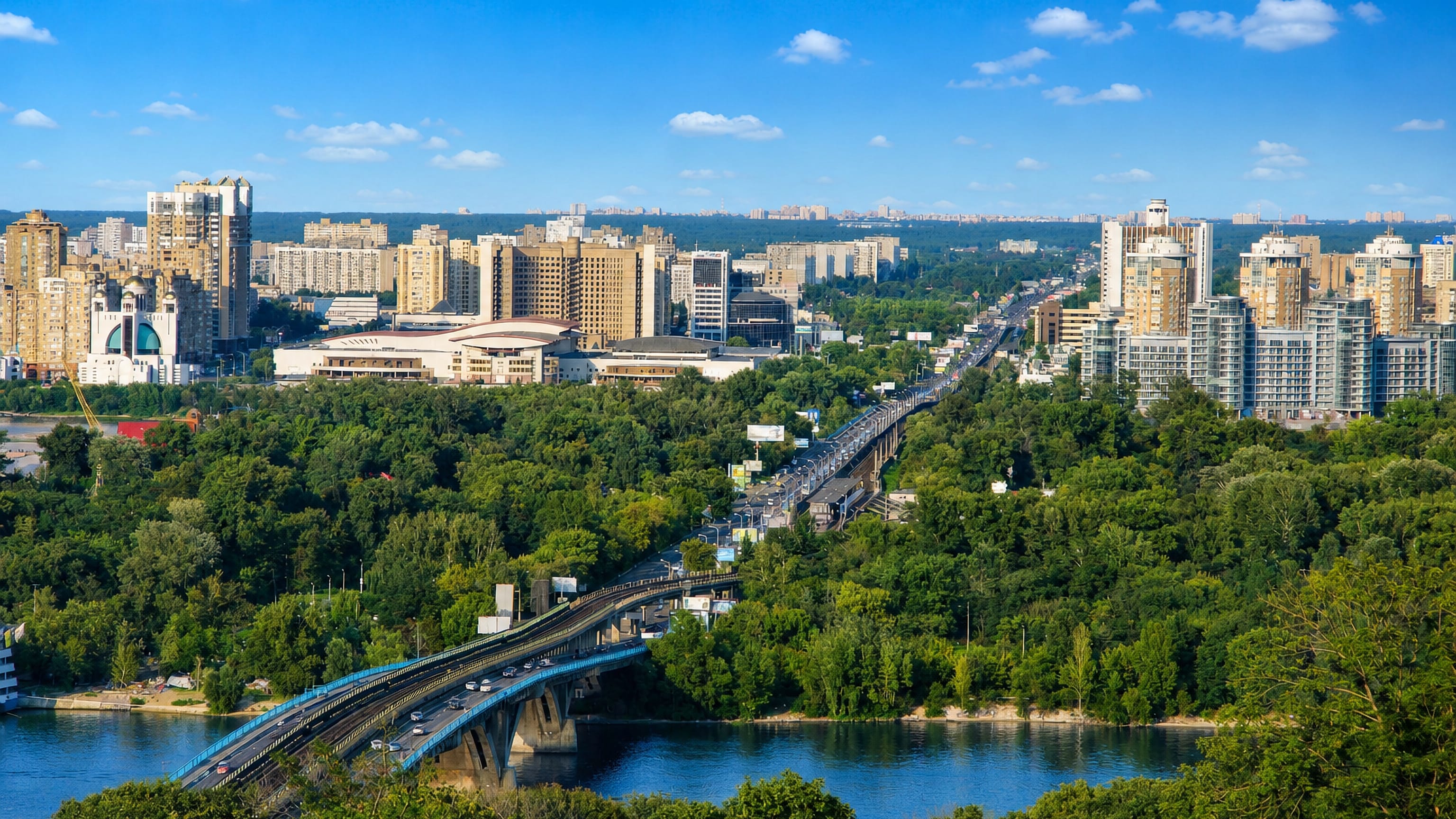 The blue Metro Bridge crossing the Dnipro toward the high-rise left bank of Kyiv's Dnipro Raion.