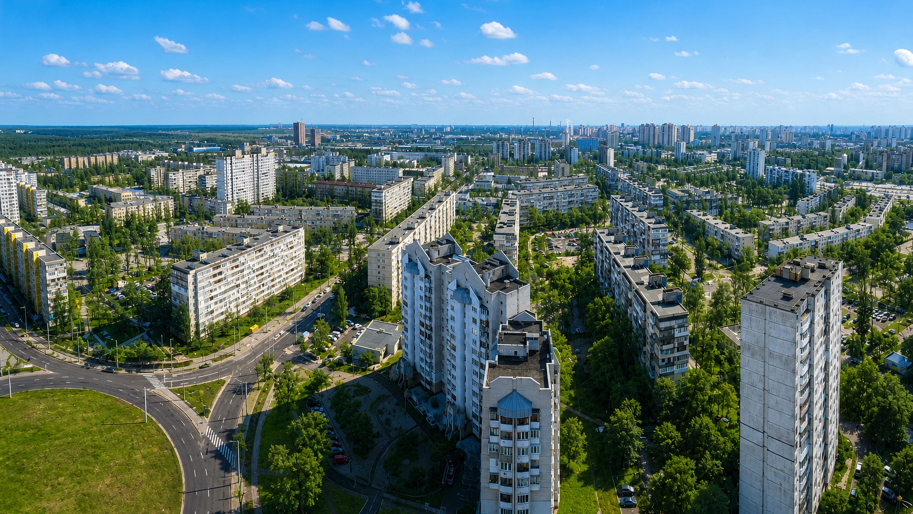 Aerial view of Lisovyi Masyv, Kyiv, rows of Soviet-era apartment blocks among green trees and wide roads.