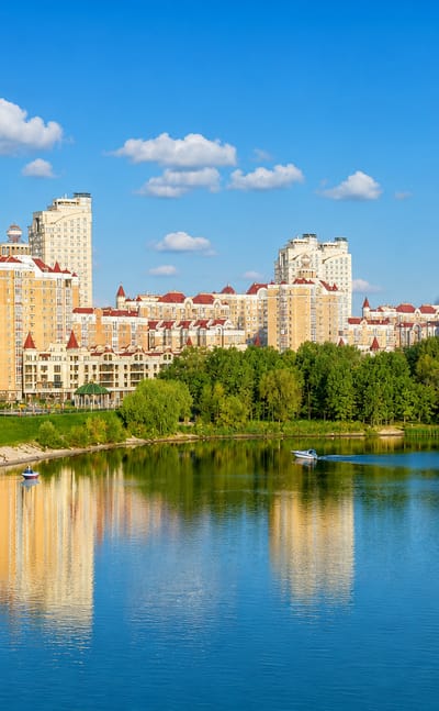 Golden-domed church and riverside apartment blocks of Kyiv's Obolon district reflected in the Dnipro.