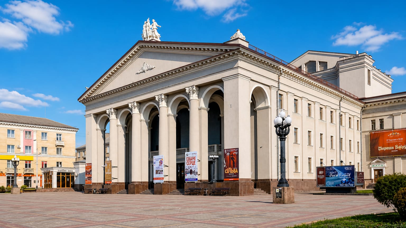Neoclassical theatre on a paved square in Rivne, Ukraine, under a bright blue sky